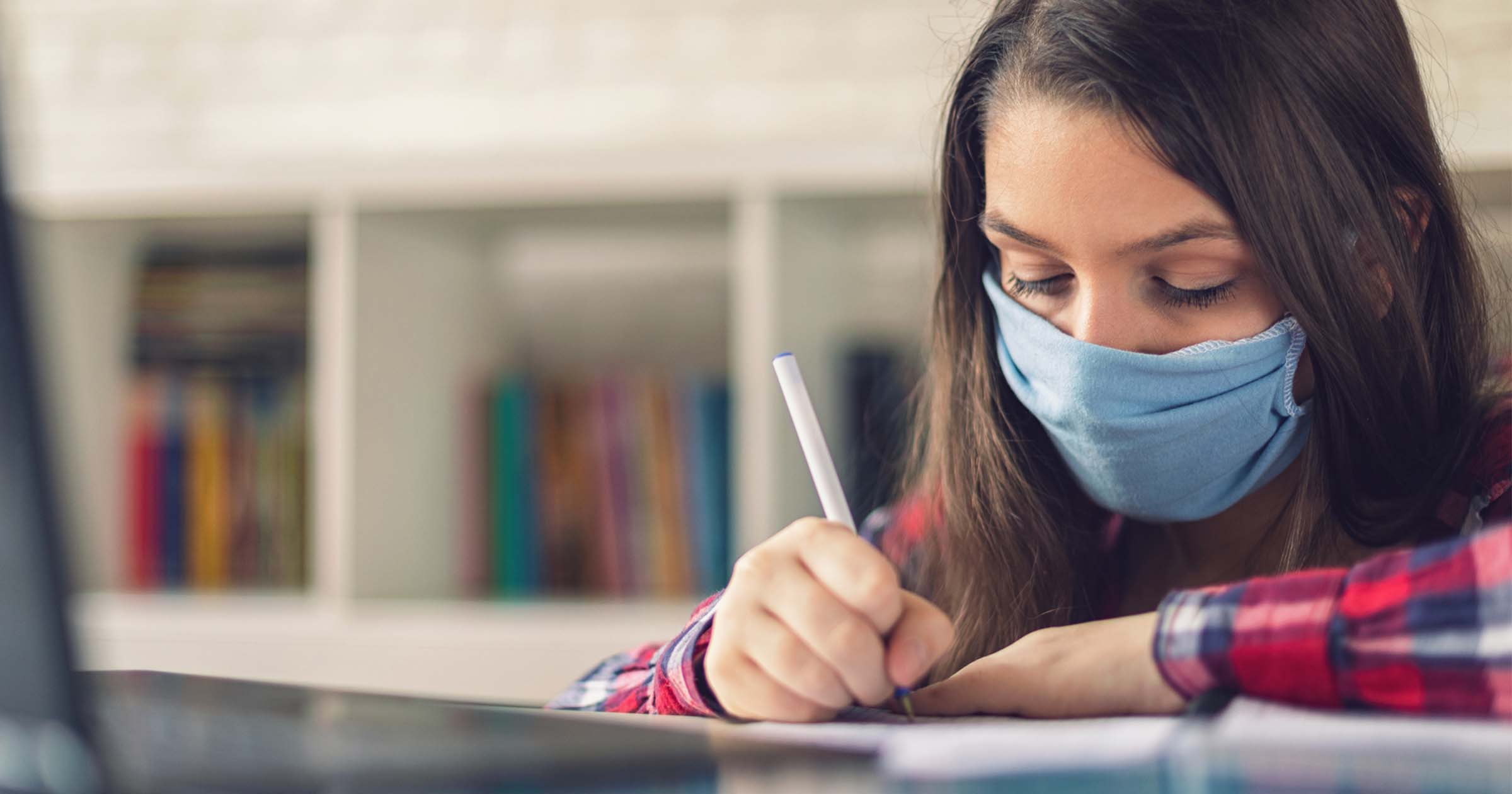 A student wears a mask while working on homework